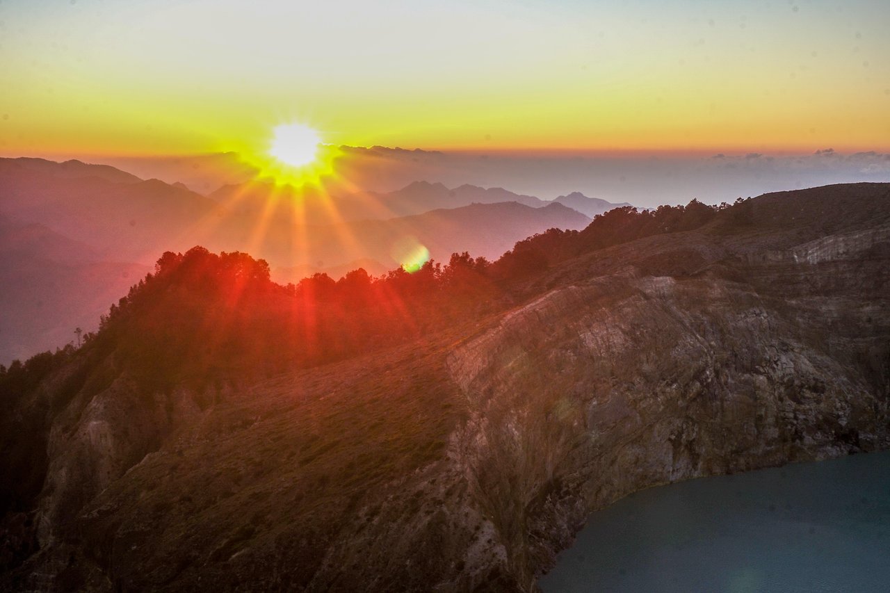 Sunrise over the Kelimutu crater rim with a turquoise lake below, Flores